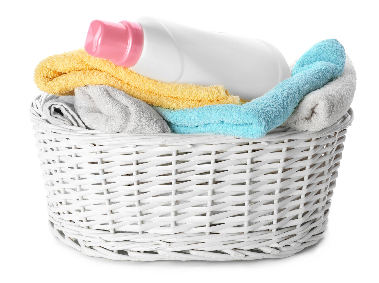 Basket with folded towels and laundry detergent on white background