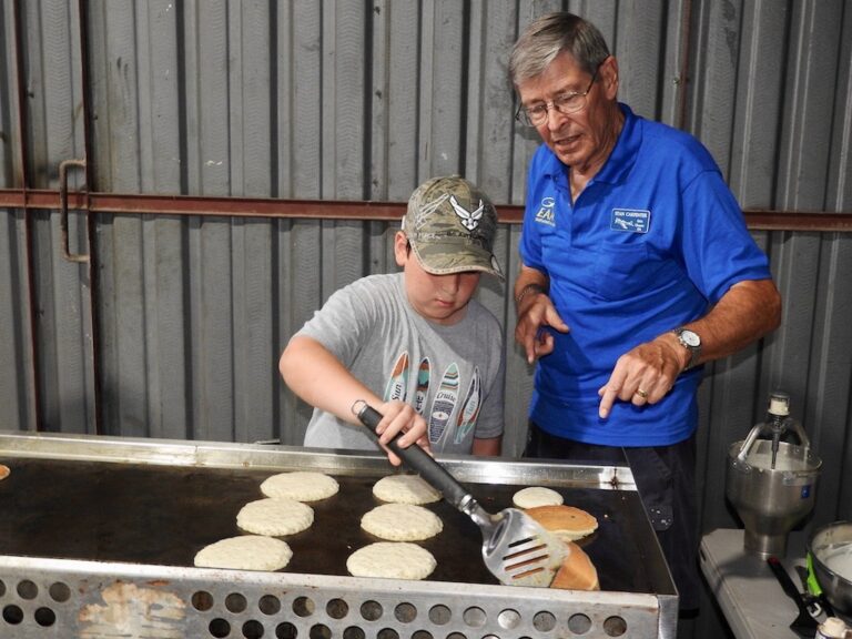 EAA Chapter 534 member Stan Carpenter takes some time to teach Mason McClintock the fine art of pancake cooking.