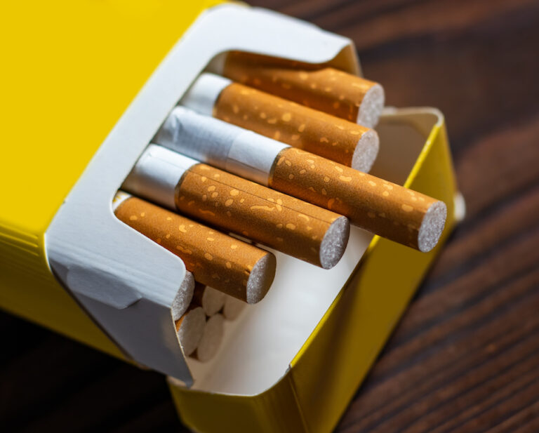 Cigarettes in a pack. Yellow filter. Harm to health. Bad habit. A pack of cigarettes on the table.